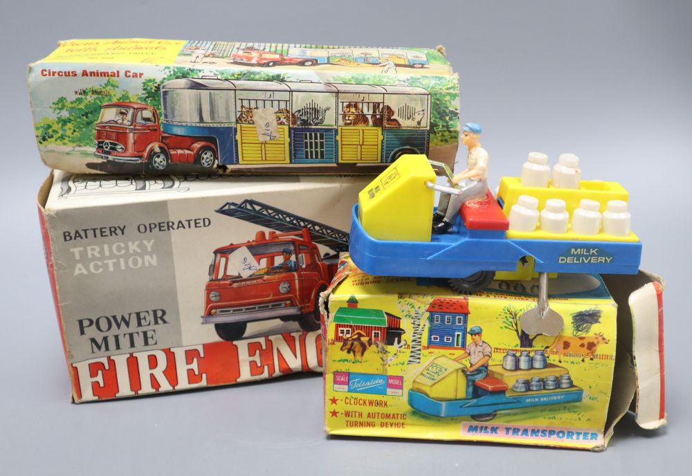 Three clockwork toy vehicles: A circus animal car, boxed; a milk transporter, boxed and a Powermite firing engine, boxed